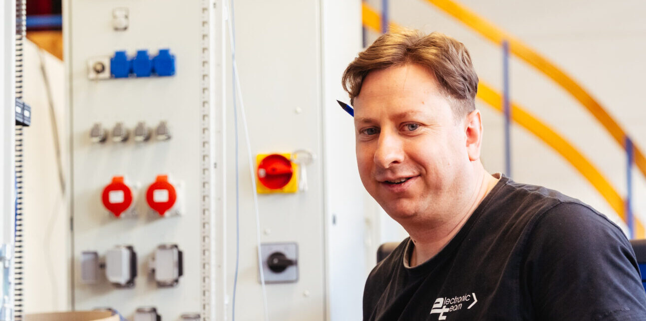 Foto eines Elektrikers von et electronic team GmbH in der Fertigung vor einem Schaltschrank.